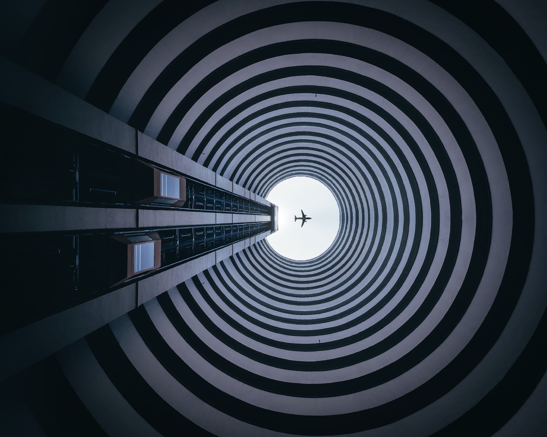 Tunnel pointing up towards an airplane in the sky